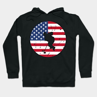 American Flag and Ice Hockey Player Silhouette, A silhouette of an ice hockey player overlaid on a distressed American flag, encapsulating patriotism and sportsmanship. Hoodie